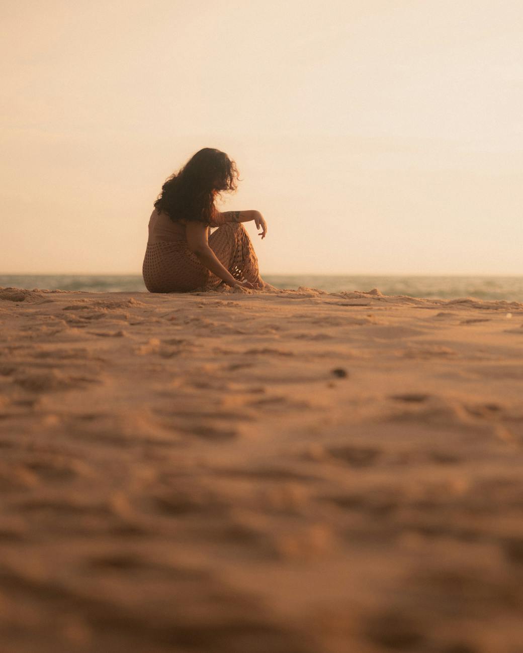 silhouette of woman sitting on beach at sunset