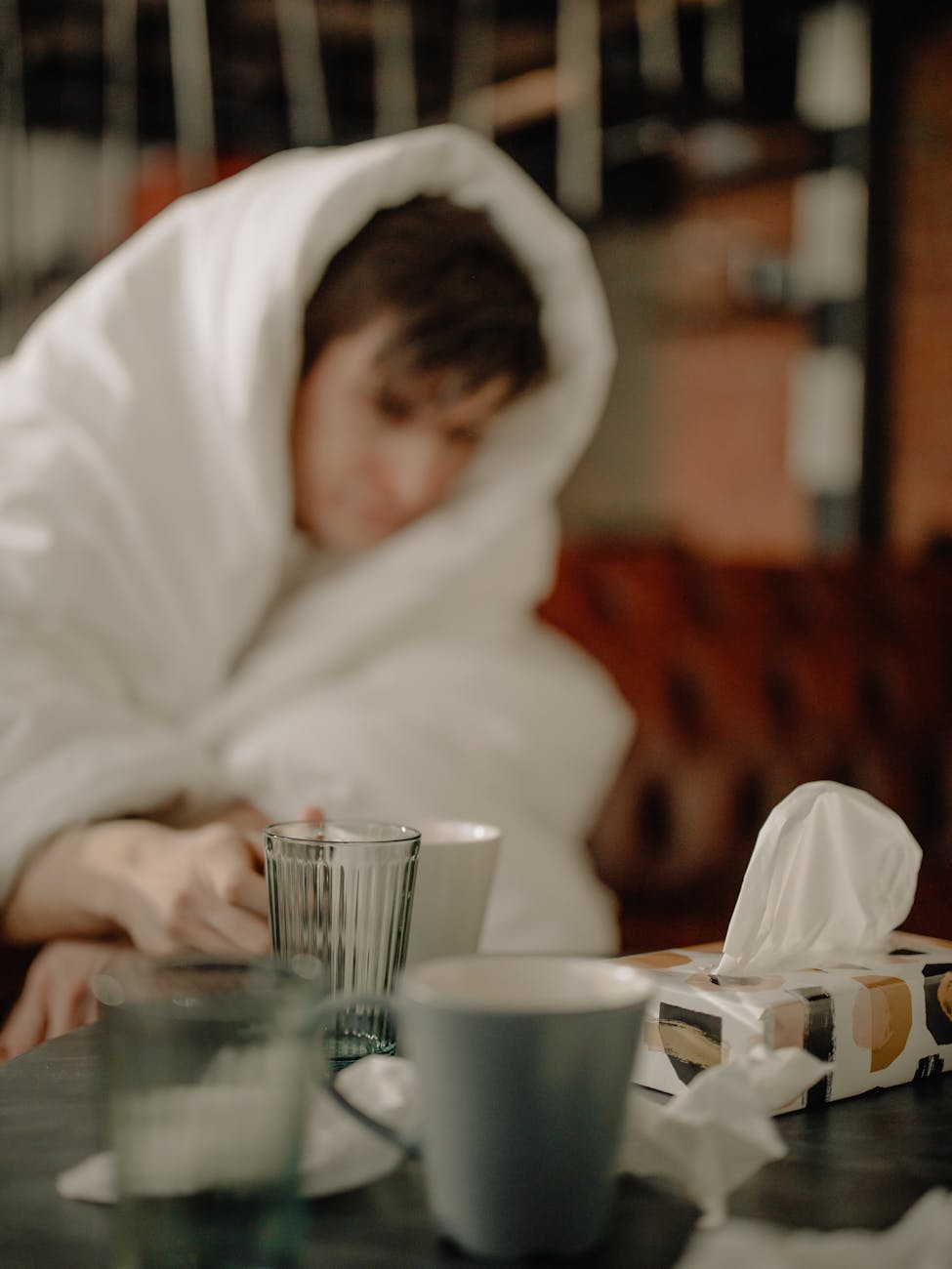 man in white hoodie sitting beside table with drinking glass