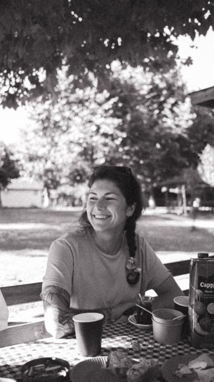 a woman smiles while sitting at a picnic table
