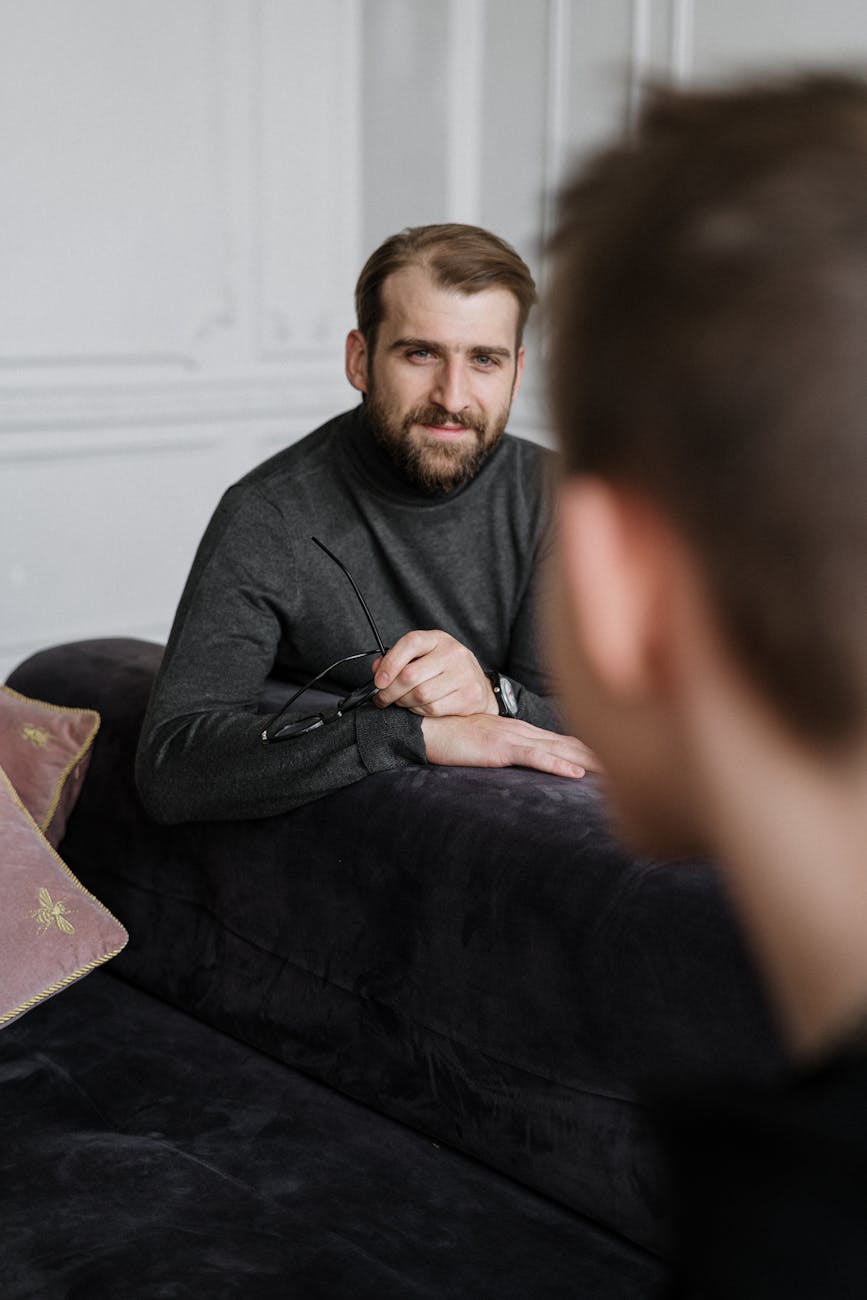 man in black crew neck t shirt sitting on black sofa