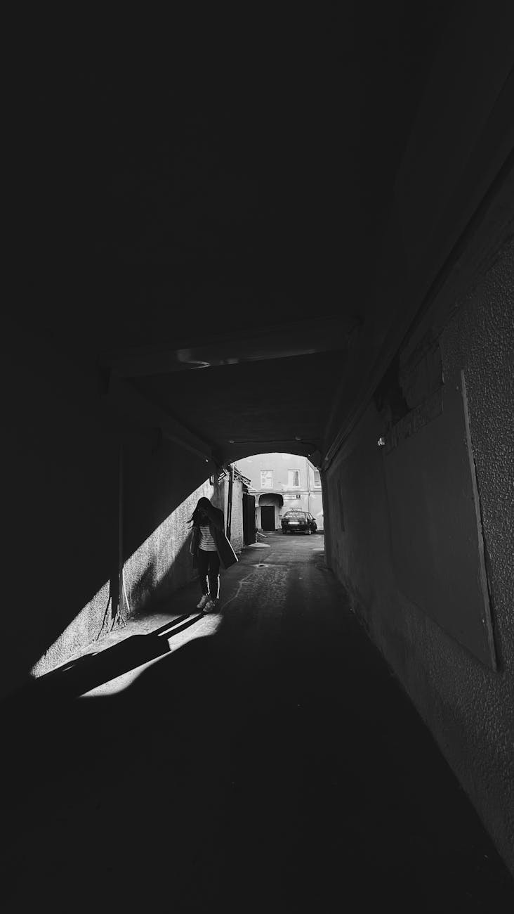 black and white picture of a woman walking in a tunnel