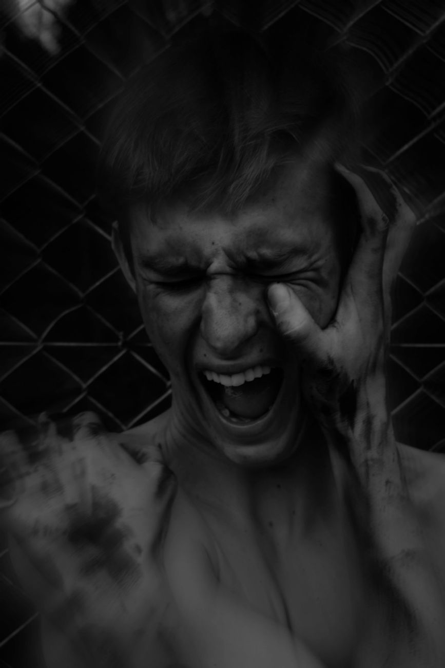 young man screaming and touching his face with dirty hands