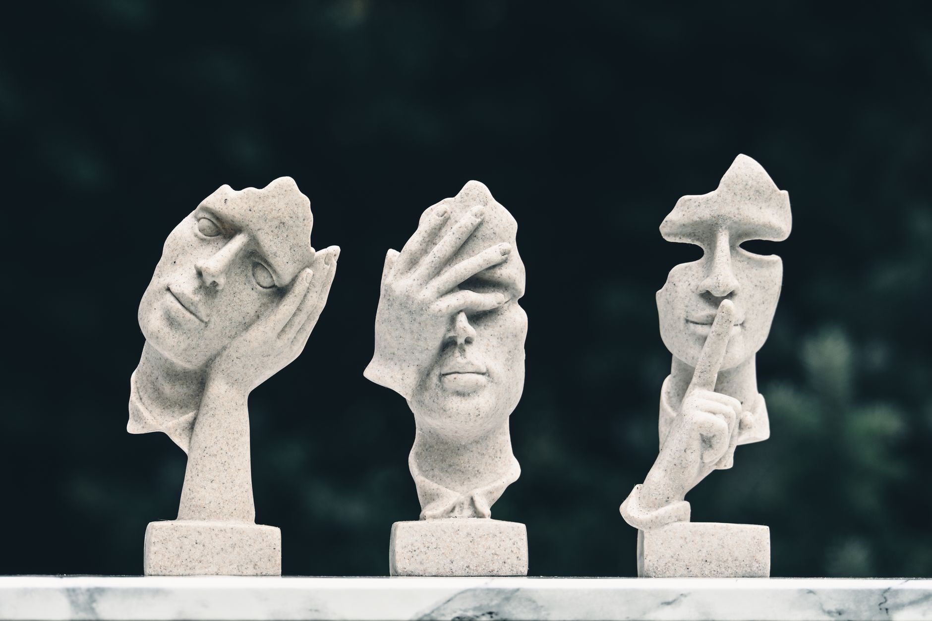 abstract stone sculptures of faces on pedestal